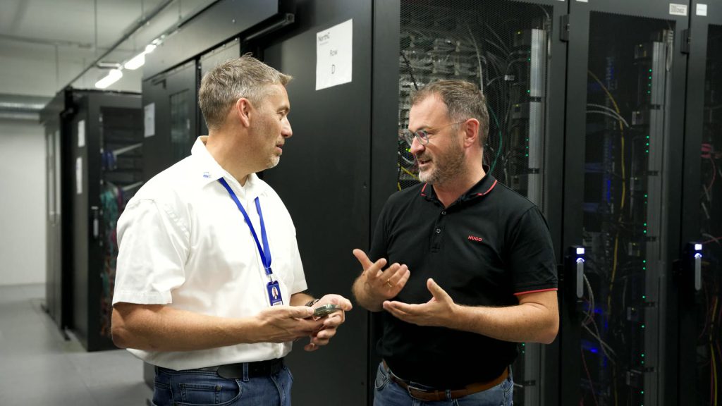 Wolfgang Asbeck und Bernhard Schlögl im Gespräch im Gang zwischen den Racks.